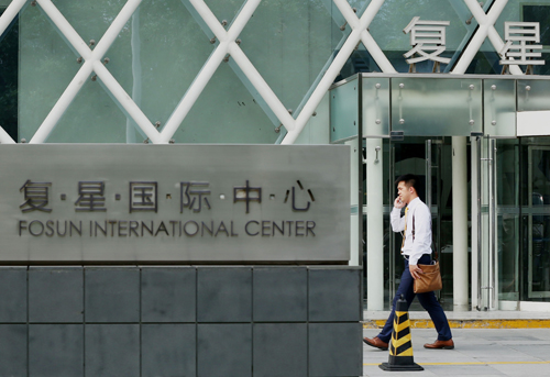 This  photo taken on July 29, shows a man walking past the headquarters building of Fosun International in Beijing (AFP  photo)